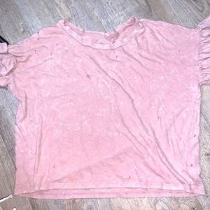 A pink shirt with ruffles on sleeves. The holes are the design.